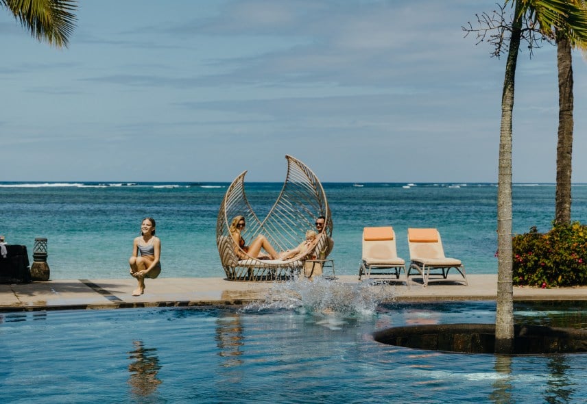 Child jumping into a pool while parents watch nearby with smiles - Heritage Awali