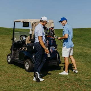 Two golfers sharing a buggy at La Réserve Golf Links with scenic surroundings