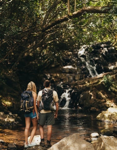  couple hiking through bel ombre nature reserve admiring a stunning waterfall