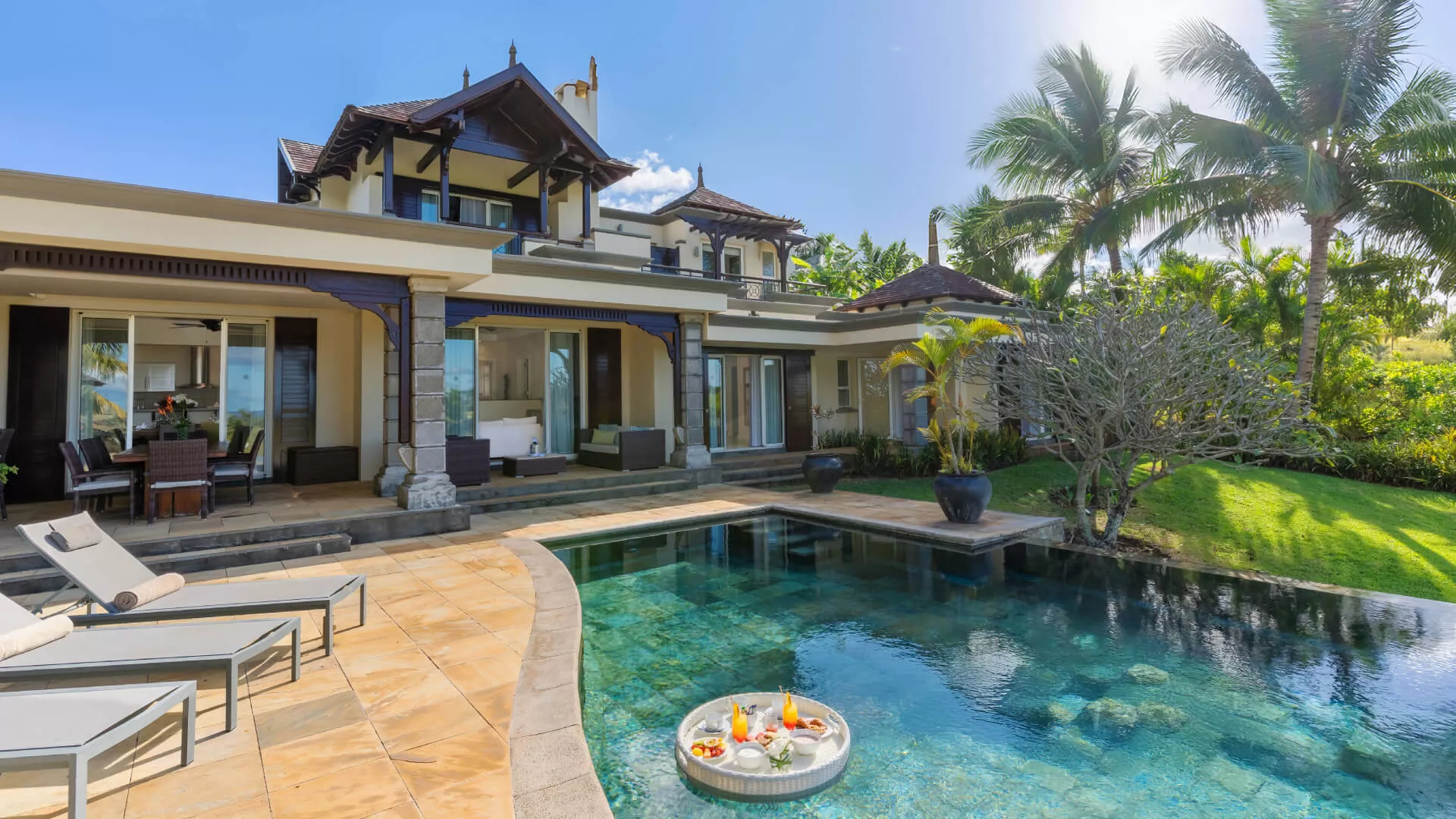 Exterior pool view of a luxury three-bedroom villa featuring a floating breakfast setup