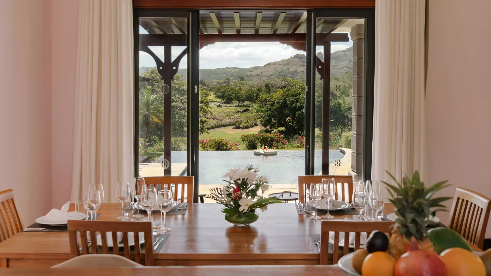 Front view of dining table with pool backdrop in a luxury 4-bedroom villa