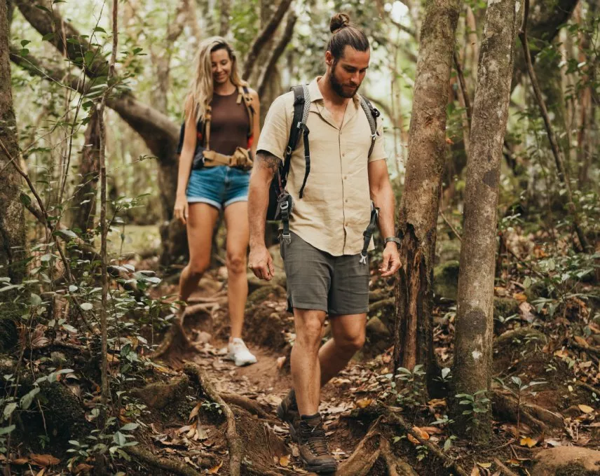 A couple strolling the shaded trails of Bras d'Eau National Park, surrounded by beautiful lush trees and the sounds of nature.