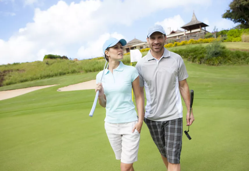 A couple strolling across a lush green golf course, enjoying a relaxing outdoor experience - Heritage Golf Club