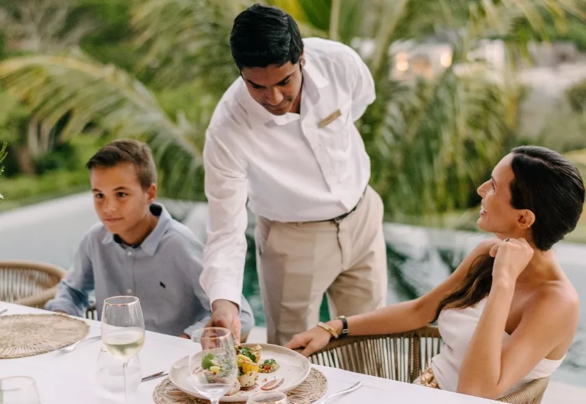 A family with young children sitting at a table being served a meal by a waiter - Heritage the Vilals
