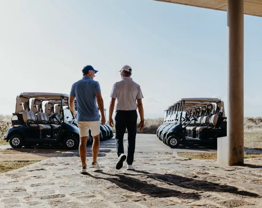 Members of Heritage Golf Club engaged in conversation near the clubhouse on a sunny day