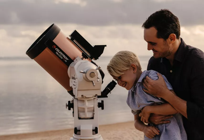 Father and son stargazing through a telescope during a nighttime celestial stargazing experience