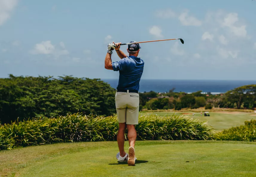 Golfer swinging with a scenic ocean view in the background