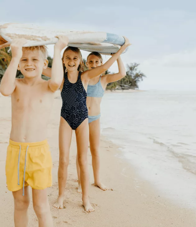 Kids holding a surfboard on the beach