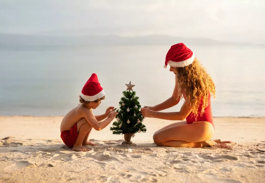 Mother and son decorating a Christmas tree on the beach in Mauritius