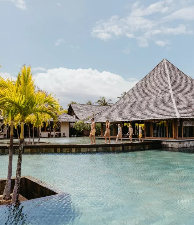 Family strolling beside a sparkling pool