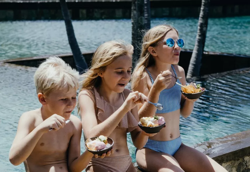 Kids enjoying delicious ice cream by the pool on a sunny day