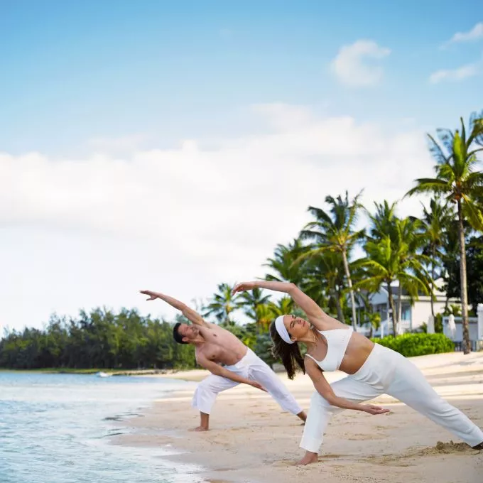 couple morning yoga on tropical beach at heritage resort mauritius