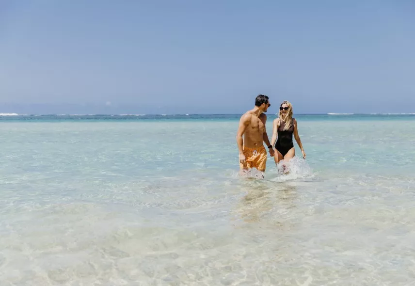 couple marchant dans le paisible lagon bleu d’Heritage Awali