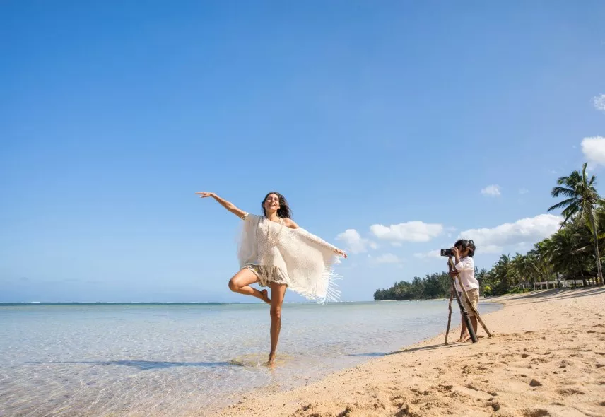 woman with child clicking pictures on the sandy beach heritage resorts