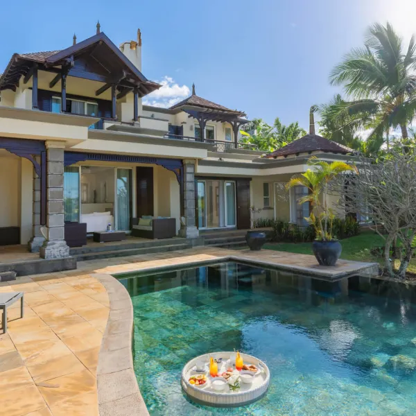 Exterior pool view of a luxury three-bedroom villa featuring a floating breakfast setup
