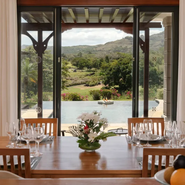 Front view of dining table with pool backdrop in a luxury 4-bedroom villa