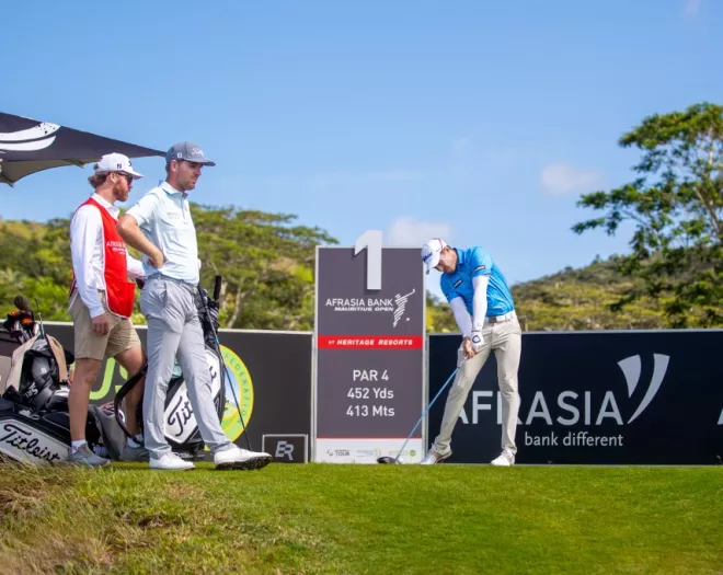 Golfer mid-swing during the AfrAsia Bank Mauritius Open 2025, with the course and spectators in the background