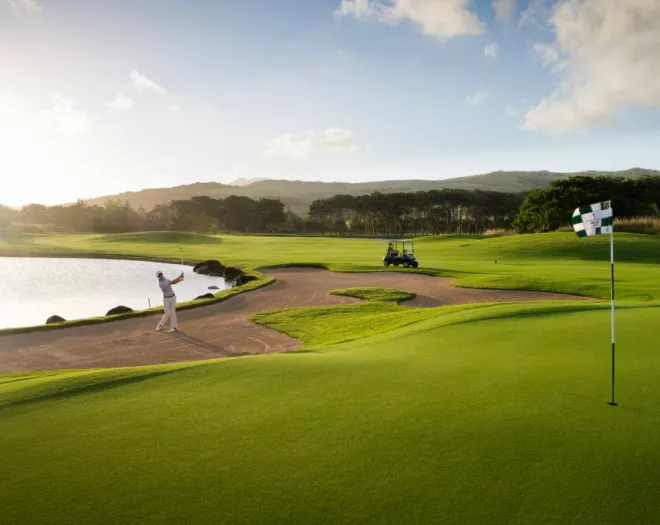 Golfer teeing off early in the morning, with soft sunlight and calm course conditions
