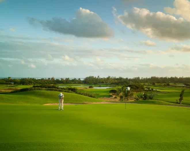 Golfer teeing off early in the morning at Le Château Golf Course, with soft light over manicured parkland fairways
