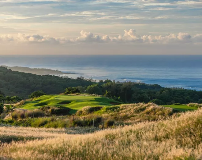 A scenic view over La Réserve Golf Links with the ocean in the background, showcasing green fairways and tropical surroundings
