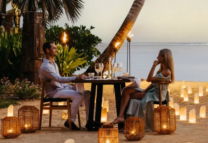 Couple enjoying a beachfront candlelit dinner in the evening, Mauritius
