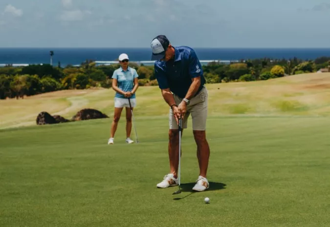 Golfer swinging at La Réserve Golf Links with panoramic landscape view