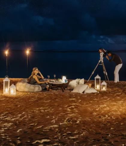 Couple enjoying a star gazing experience on the beach at night