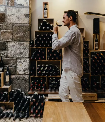 Man drinking from a glass of wine while walking across the wine cellar